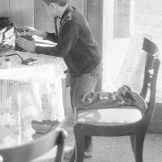 Boy playing with model train set on a table.