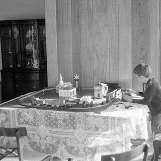 Boy playing with model train set on a table.
