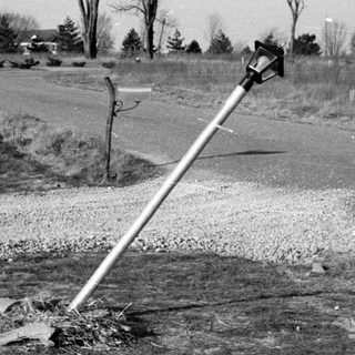 Tilted street light beside a rural road.