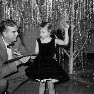 Man and girl in front of tinsel backdrop.