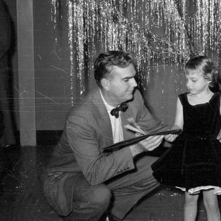 Man and girl in front of tinsel backdrop.