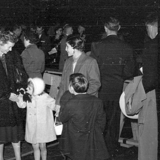 Group of people in formal coats at night.