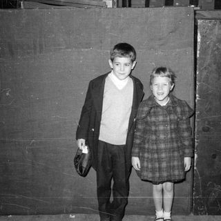 Two children posing against a dark wall.