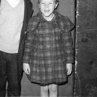 Two children posing against a dark wall.