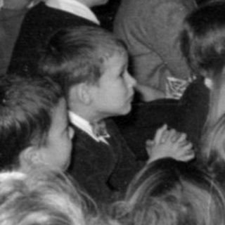 Group of children and adults near tinsel decorations.