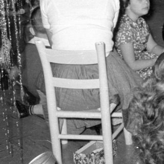 Group of children and adults near tinsel decorations.