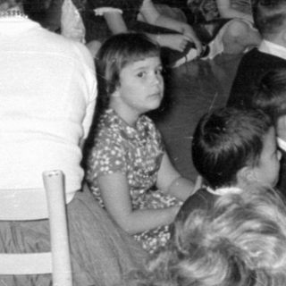 Group of children and adults near tinsel decorations.