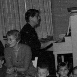 Group of children and adults near tinsel decorations.