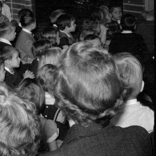 Group of children and adults near tinsel decorations.