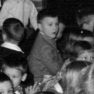 Children gathered near a fireplace with tinsel decorations.