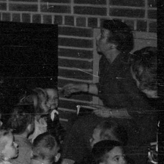 Children gathered near a fireplace with tinsel decorations.