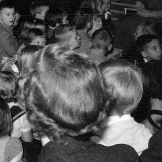 Children gathered near a fireplace with tinsel decorations.