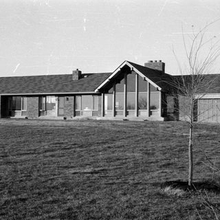 Mid-century modern brick house on a grassy lot.
