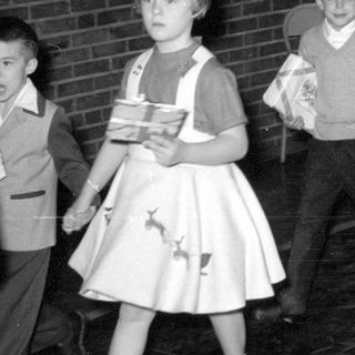 Children in formal wear carrying wrapped gifts.