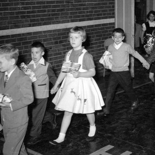 Children in formal wear carrying wrapped gifts.