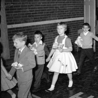 Children in formal wear carrying wrapped gifts.