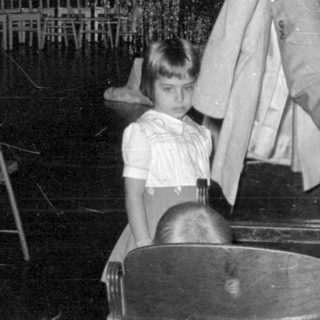 Man holding garment near a girl in a hall.