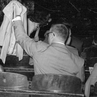 Man holding garment near a girl in a hall.