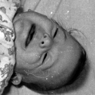 Infant in floral pajamas lying in a crib.
