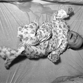 Infant in floral pajamas lying in a crib.