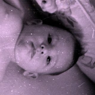 Infant in a diaper lying in a crib.
