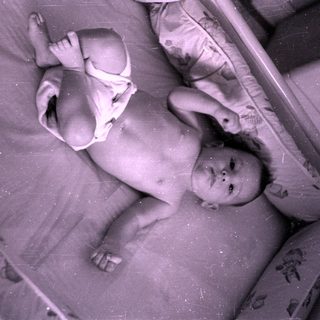 Infant in a diaper lying in a crib.