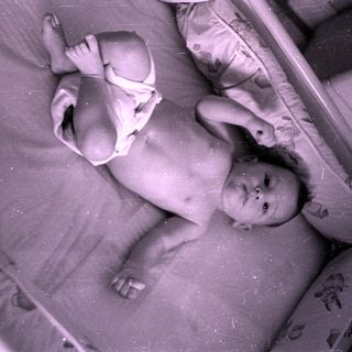Infant in a diaper lying in a crib.