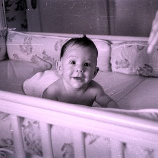 Infant lying in a floral patterned crib.
