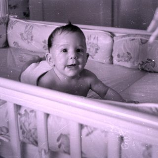 Infant lying in a floral-lined crib.