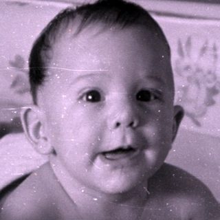 Infant lying in a floral-lined crib.