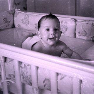 Infant lying in a floral-lined crib.