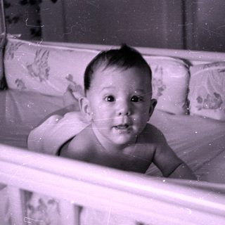 Infant lying in a floral patterned crib.
