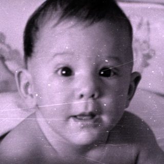 Infant lying in a floral patterned crib.