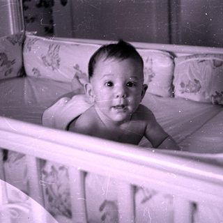 Infant lying in a floral patterned crib.