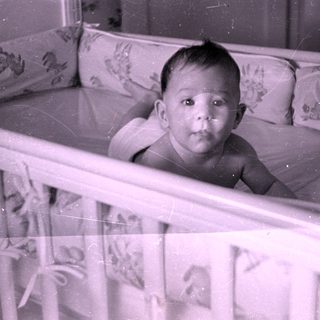Infant lying in a floral-patterned crib.