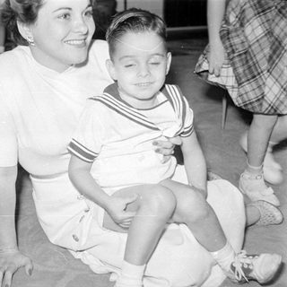 Woman and boy in sailor suit on carpet.