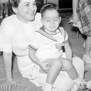 Woman and boy in sailor suit on carpet.