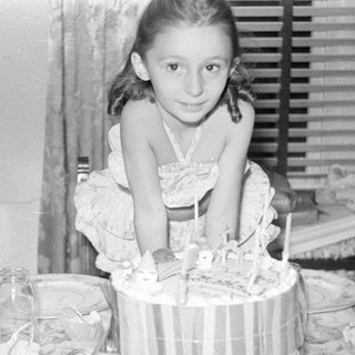 Young girl sitting behind a birthday cake.