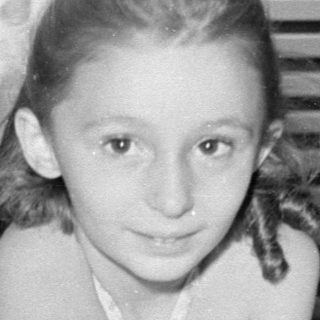 Young girl sitting behind a birthday cake.