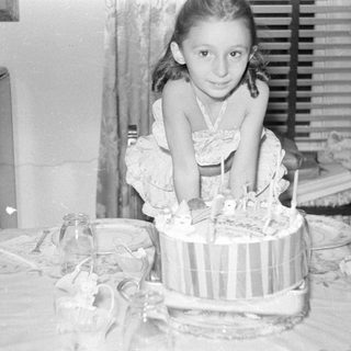 Young girl sitting behind a birthday cake.