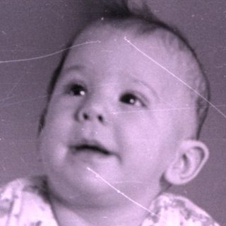 Infant in floral pajamas lying on a bed.