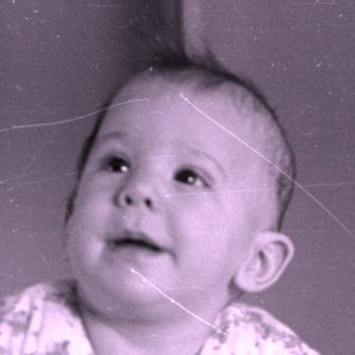 Infant in floral pajamas lying on a bed.