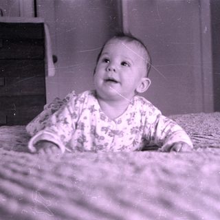 Infant in floral pajamas lying on a bed.