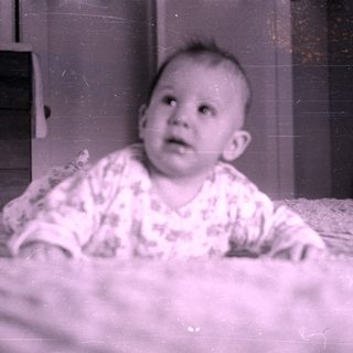 Infant in patterned clothing lying on a bed.