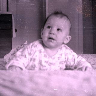 Infant in patterned clothing lying on a bed.