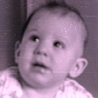 Infant in patterned clothing lying on a bed.