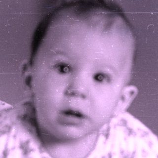 Baby in patterned pajamas on a bed.