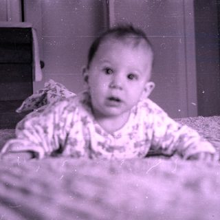 Baby in patterned pajamas on a bed.