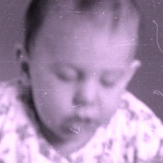 Infant in patterned pajamas lying on a bed.