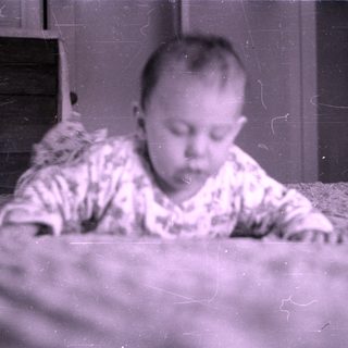 Infant in patterned pajamas lying on a bed.